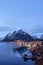 Reine, snow covered mountains in the background and the fishing cabins Rorbu in the foreground, Lofoten Islands, Norway
