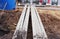 reinforced concrete beams of square section lie on the ground at the construction site near the house.