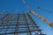 A reinforced steel rebar foundation work and tower crane against the blue sky. Construction. Building construction