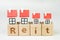 Reit, Real estate investment trust concept, miniature houses on cube wooden block with alphabet combine the word Reit on white