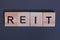 Reit, Real estate investment trust from wooden letters on a gray background