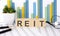 REIT word written on the wood block with chart, glasses and pencils
