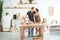 Relationship in the family with small children. Dad and mom kiss in the bright kitchen, children cook in the kitchen