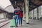 Relationship and travelling concept. Lovely woman and man cuddle while walk across railway station platform, carry suitcase,