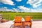Relax deck chairs in agricultural landscape. Green wheat field under blue sky view