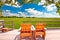 Relax deck chairs in agricultural landscape. Green wheat field under blue sky view