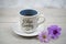 Relax Sunday. Sunday concept with happy smile on cup of morning coffee closeup, purple daisy orchid flowers on white table