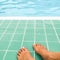 Relax time on swimming pool, feet in the water