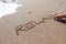 Relax word handwritten on beach sand with white feather on summer time