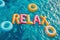 Relax word spelled out in inflatable pool floats in a summer holiday swimming pool