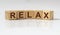 RELAX word written on wooden cube blocks on white glossy table with reflection