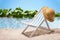 Relaxation at the beach with sun lounger and sunhat in front of a blue lagoon