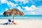 Relaxation and vacation idyllic background. Straw umbrella with sun lounger and red towel on the beach in Varadero, Cuba