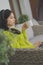 Relaxation and wellbeing concept. Young asian woman drinking cup of tea while resting on the balcony sofa with laptop