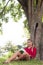 Relaxed 20s girl reading a summer book under a tree