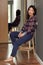 Relaxed adult asian woman sitting on chair in hallway at home, female reflection in mirror of apartment closet