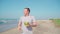 Relaxed adult guy standing and drinking coconut on sandy beach. Handsome man enjoying tropical drink, sipping coconut water