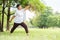 Relaxed Asian Senior woman in white cloth doing stretching workout her arms at park. Smiling Elderly Thai Female enjoying