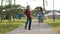 A relaxed attractive middle-aged man with long gray hair on a kick-scooter and a young woman with dyed hair greet and