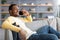 Relaxed black man having conversation on phone, home interior