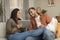Relaxed black spouses chilling together at home, man and woman using digital tablet and smartphone, resting on sofa