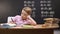 Relaxed bored schoolboy sitting at desk, unwilling to prepare math homework