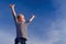 Relaxed boy breathing fresh air raising arms over blue sky at summer. Dreaming, freedom and traveling concept