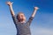 Relaxed boy breathing fresh air raising arms over blue sky at summer. Dreaming, freedom and traveling concept