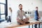 Relaxed businessman meditating in lotus position while coworkers moving