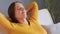 Relaxed calm adult brown haired woman taking nap during the day sitting down on couch raised her arms sleeping on sofa at home