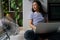 Relaxed carefree Asian woman sits on floor with laptop on lap and enjoying wind coming from fan