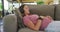 Relaxed caucasian pregnant woman lying on sofa and listening to music