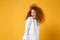 Relaxed cheerful stunning young redhead woman girl in white shirt posing isolated on yellow orange wall background