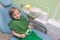 Relaxed contented child man sitting in chair at dentist in hands of jaw with white teeth toy and props. Painless treatment and