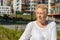 Relaxed elder woman sitting on a bench looking at camera and smiling. Happy old age concept