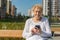 Relaxed elder woman sitting on a bench with smartphone. Happy old age concept