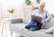 Relaxed elderly woman using laptop on sofa at home