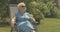 Relaxed elegant senior woman sitting in chair outdoors and drinking water. Portrait of carefree Caucasian lady in