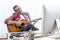 Relaxed entrepreneur singing and playing guitar at home-office desk