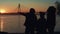 Relaxed family silhouette standing on river shore. Beautiful golden sunset time.