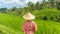 Relaxed fashionable caucasian woman wearing red asian style kimono and traditional asian paddy hat looking at beautiful