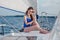 Relaxed girl sitting on sailboat, enjoying mild sunlight, fashi