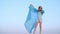 Relaxed girl in transparent blue tunic on wind standing in desert on sky landscape. Beautiful young girl enjoying wind