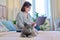 Relaxed gray cat lying on bed, woman with laptop in out of focus