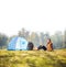 Relaxed hiker sitting next to a blue tent