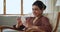 Relaxed Indian woman resting on armchair with smartphone