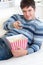 Relaxed man with popcorn showing the remote