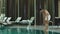 Relaxed man walking poolside at luxury hotel. Man swimming at pool alone.