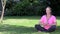 Relaxed middle aged woman in her forties outside cross legged practicing yoga in prayer