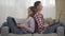 Relaxed millennial couple leaning at each other on couch and typing on laptop keyboards. Side view portrait of absorbed